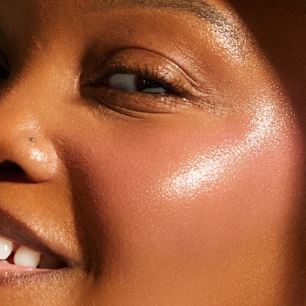Close-up of deep skin tone showing smooth, radiant cheek texture with a warm luminous glow from the Annadea Power Walk Blush Serum in Soft Step, showcasing the antioxidant defense formula's skin-smoothing and protecting results