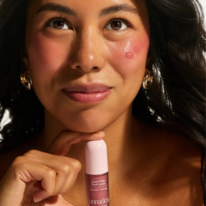 Model with medium skin tone showing Annadea Power Walk Blush Serum in Rose Trail dotted on cheeks before blending, demonstrating the serum application technique for a natural buildable flush