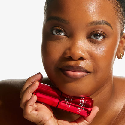 Model with luminous, glowing skin resting the Annadea To Dew Glow Serum against her jaw, highlighting the serum's radiance-boosting and skin-nourishing results