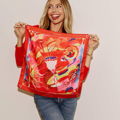Model holding up the Annadea Lived in Color limited-edition silk scarf, showing the full vibrant abstract design by artist Henriette Arcelin